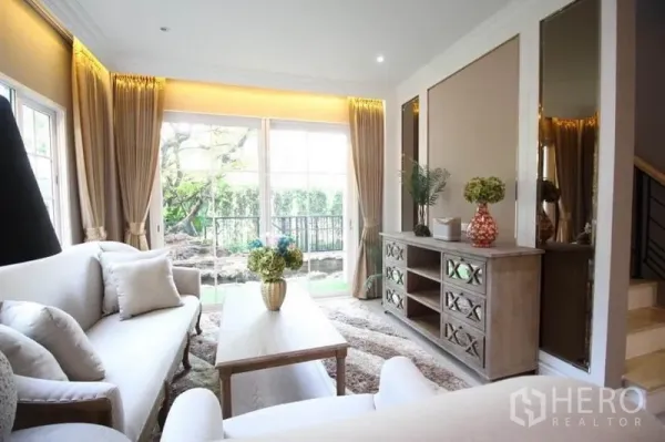 Detached House for rent or sale in Lat Phrao, Bangkok - Cozy living area with sliding glass doors to the garden, wooden console and shag rug.