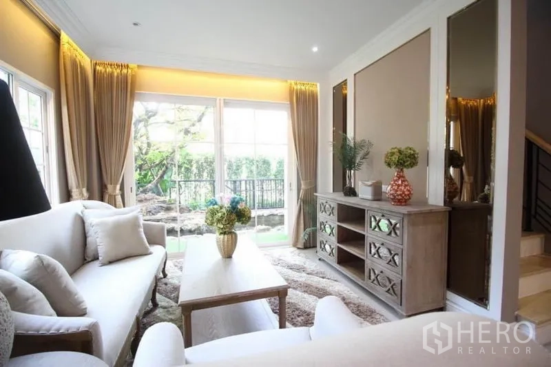 Detached House for rent or sale in Lat Phrao, Bangkok - Cozy living area with sliding glass doors to the garden, wooden console and shag rug.