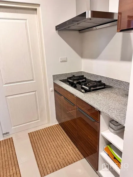 Detached House for sale in Prawet, Bangkok - Compact kitchen with granite countertop, gas hob and stainless-steel hood.