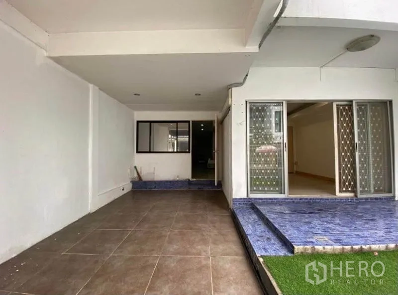 Townhouse for rent in Khlong Toei, Bangkok - Covered carport and front patio with sliding doors and blue-tiled steps at a Bangkok townhouse.
