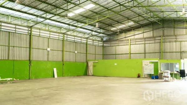 Warehouse for rent in Thanyaburi, Pathum Thani - Bright warehouse bay with green lower walls, ventilation panels and overhead industrial lighting.