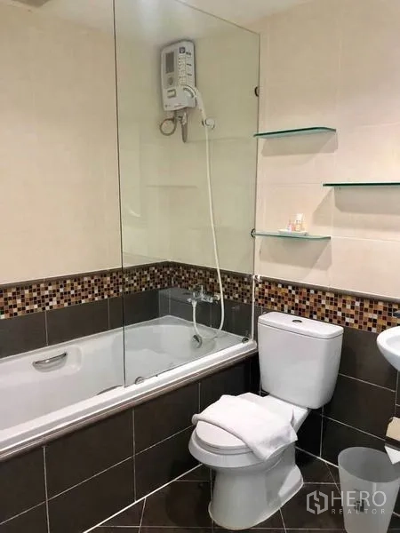 Condominium for rent in Khlong Toei, Bangkok - Bathroom with bathtub, glass screen and mosaic tile accent.