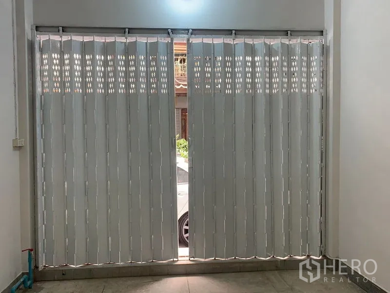 Shophouse for rent in Khlong Toei, Bangkok - Interior view of metal accordion shopfront shutters partially open to the street.