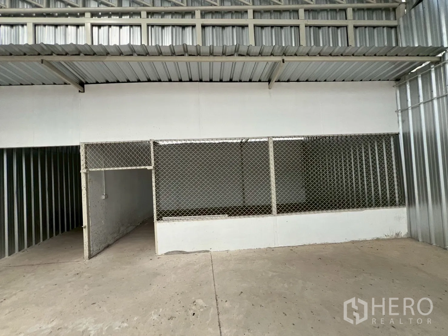 Warehouse for rent in Min Buri, Bangkok - Secure mesh-enclosed storage room and doorway at the back of the warehouse under a metal awning.