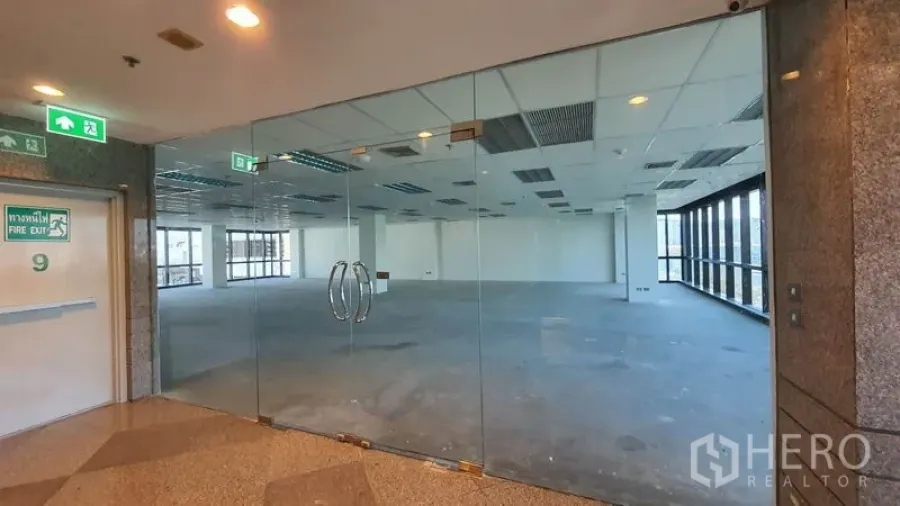 办公空间 出租在Watthana, Bangkok - 玻璃双开门入口，宽敞开放式办公楼层，网格吊顶与照明。