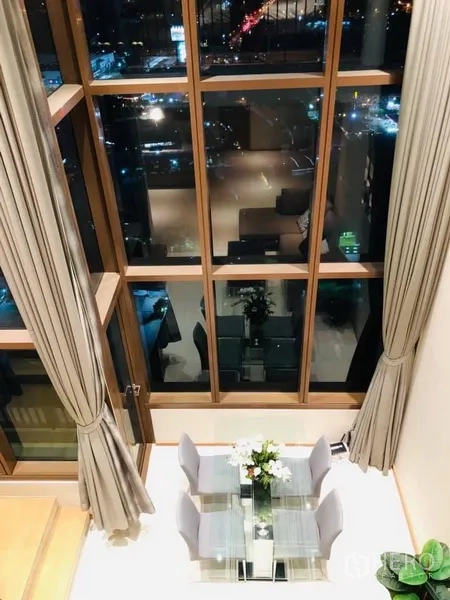 Condominium for rent in Khlong Toei, Bangkok - Double-height living and dining area with floor-to-ceiling windows and night city view in a Khlong Toei, Bangkok condo.