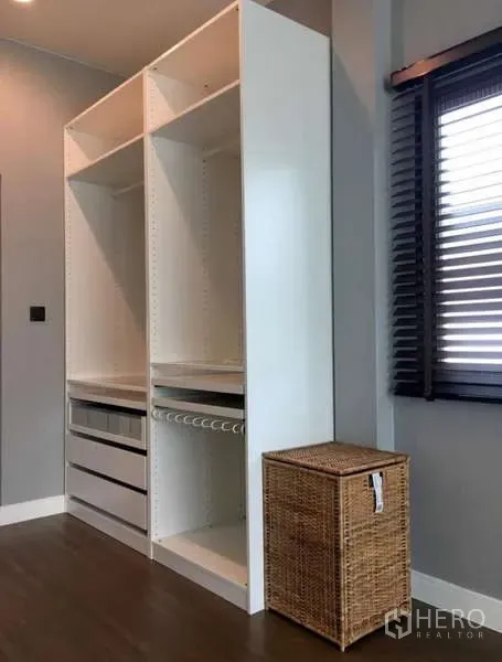 Detached House for rent in Bang Kapi, Bangkok - Open white wardrobe beside a window with blinds and a wicker basket.