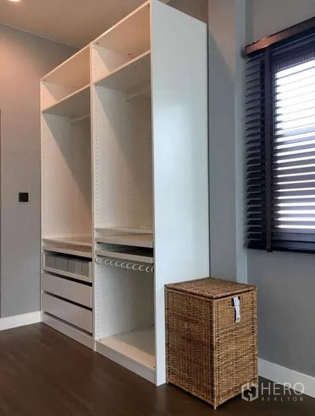 Detached House for rent in Bang Kapi, Bangkok - Open white wardrobe beside a window with blinds and a wicker basket.