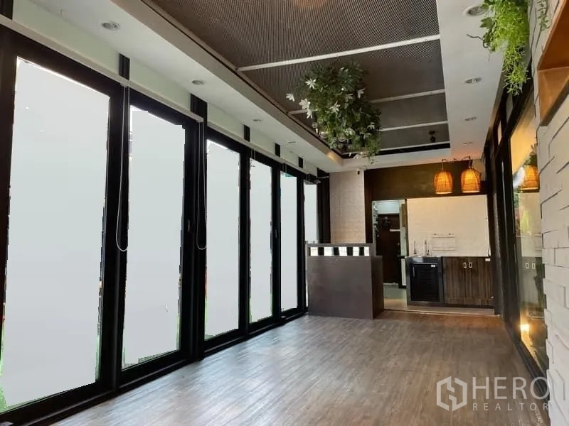 Retail Space for rent in Watthana, Bangkok - Open‑plan shop with full‑height folding glass panels, reception counter, pendant lamps and wood flooring.