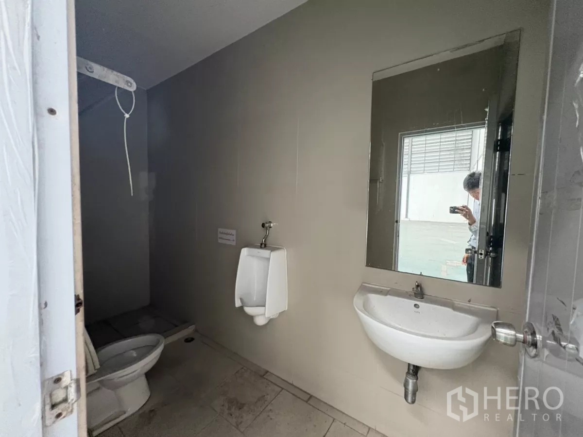 Warehouse for rent in Bang Phli, Samut Prakan - Warehouse restroom with sink, urinal, and toilet near the loading bay.