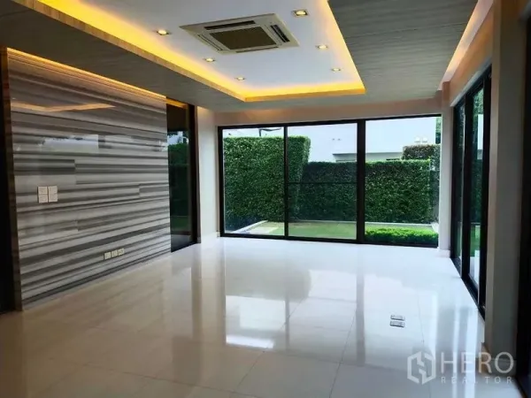 Detached House for rent or sale in Mueang Nonthaburi, Nonthaburi - Open living area with marble accent wall, recessed lighting and sliding glass doors to the garden.