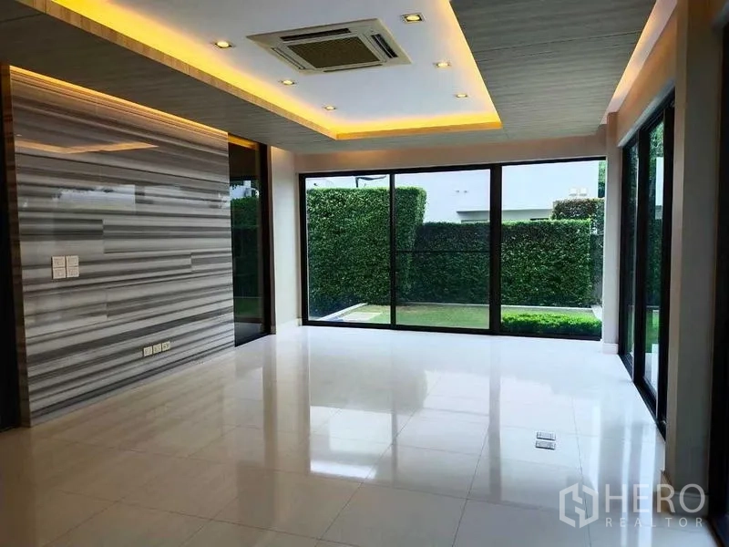 Detached House for rent or sale in Mueang Nonthaburi, Nonthaburi - Open living area with marble accent wall, recessed lighting and sliding glass doors to the garden.