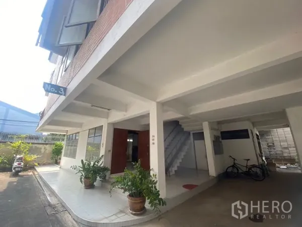 Home Office for rent in Khlong Toei, Bangkok - Ground floor covered parking area with stairwell and potted plants.