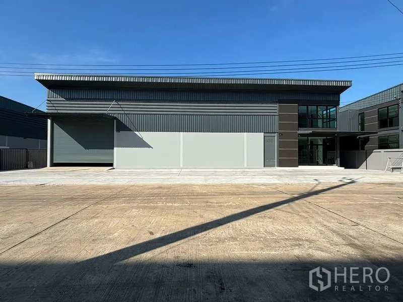 Factory for rent in Bang Bo, Samut Prakan - Modern factory facade with large electric roller shutter and spacious concrete apron.