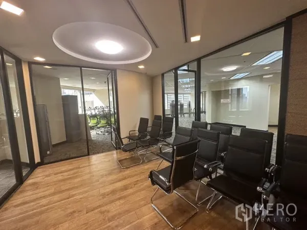 Office Space for rent - Training room with rows of black chairs, wood flooring and surrounding glass-partitioned meeting rooms.