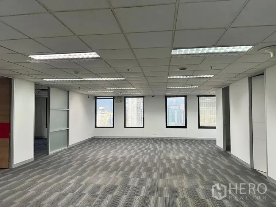 Office Space for rent in Khlong Toei, Bangkok - Large open office area with fluorescent lighting, windows and a glass partition wall.