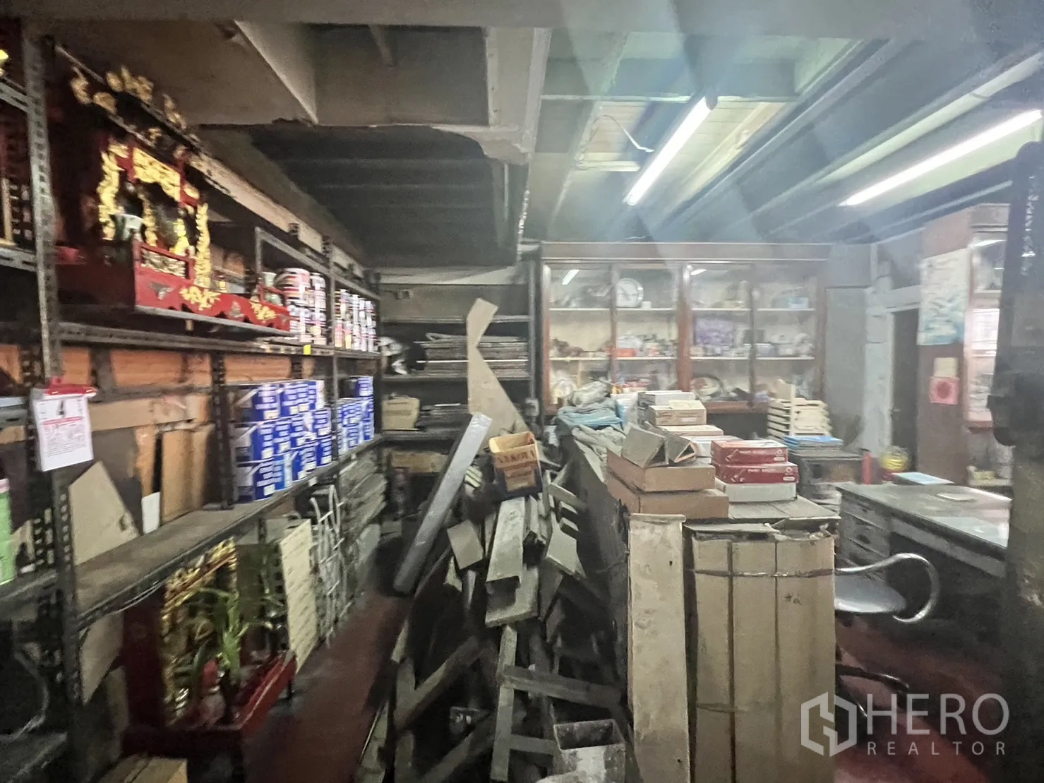 零售空间 出租在Watthana, Bangkok - 后部仓储区，堆放木板、金属货架与油漆桶，工业风格