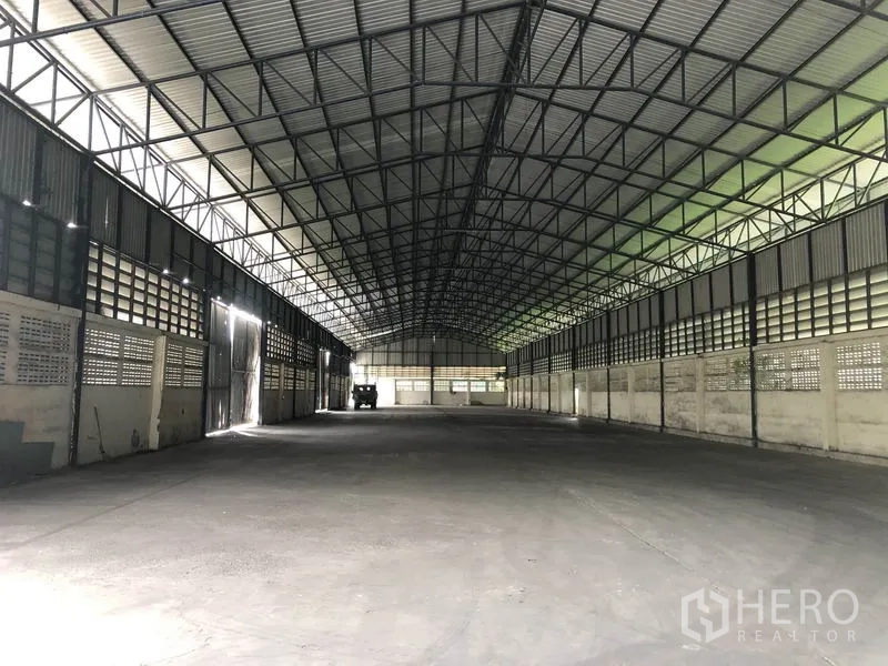Warehouse for rent in Pathum Thani - Open warehouse bay showing ventilated side walls, high roof, and smooth concrete floor.