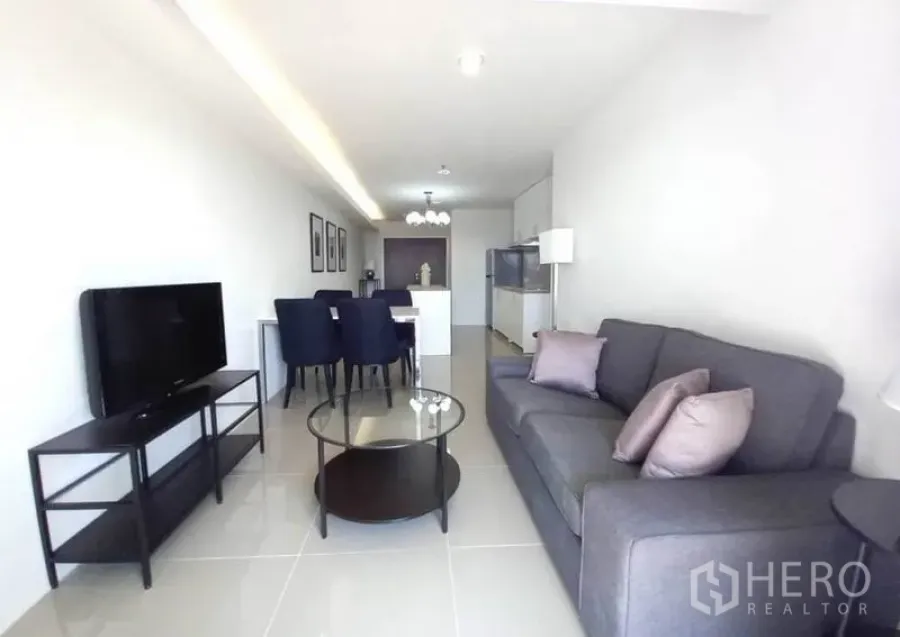 Condominium for rent in Khlong Toei, Bangkok - Bright open-plan living and dining area with gray sofa, glass coffee table, TV stand and kitchen island in a 2-bedroom condo near BTS Phrom Phong.