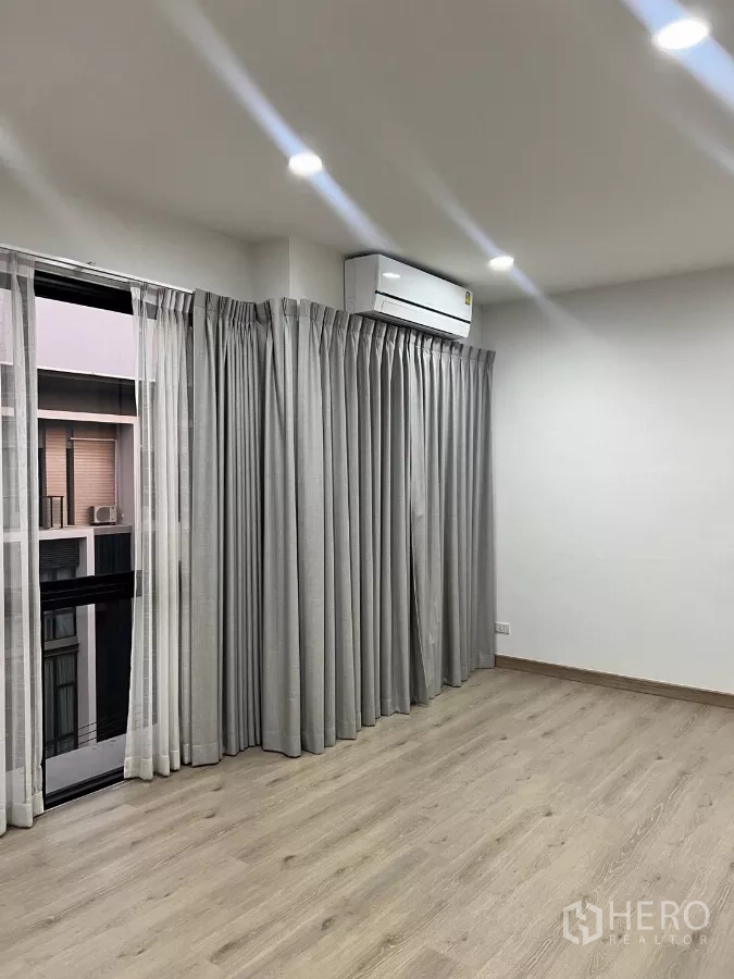 Home Office for rent in Lat Phrao, Bangkok - Corner bedroom with sliding door, grey curtains and wall-mounted air conditioner.