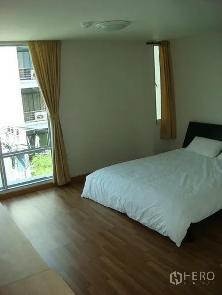 Apartment for rent in Khlong Toei, Bangkok - Spacious bedroom with double bed, floor-to-ceiling windows and curtains.