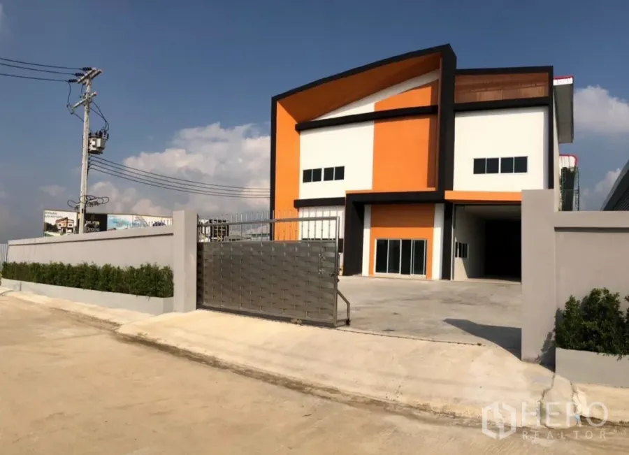 Factory for rent or sale in Mueang Samut Sakhon, Samut Sakhon - Newly built orange-and-white factory with gated driveway and parking apron in Mueang Samut Sakhon.