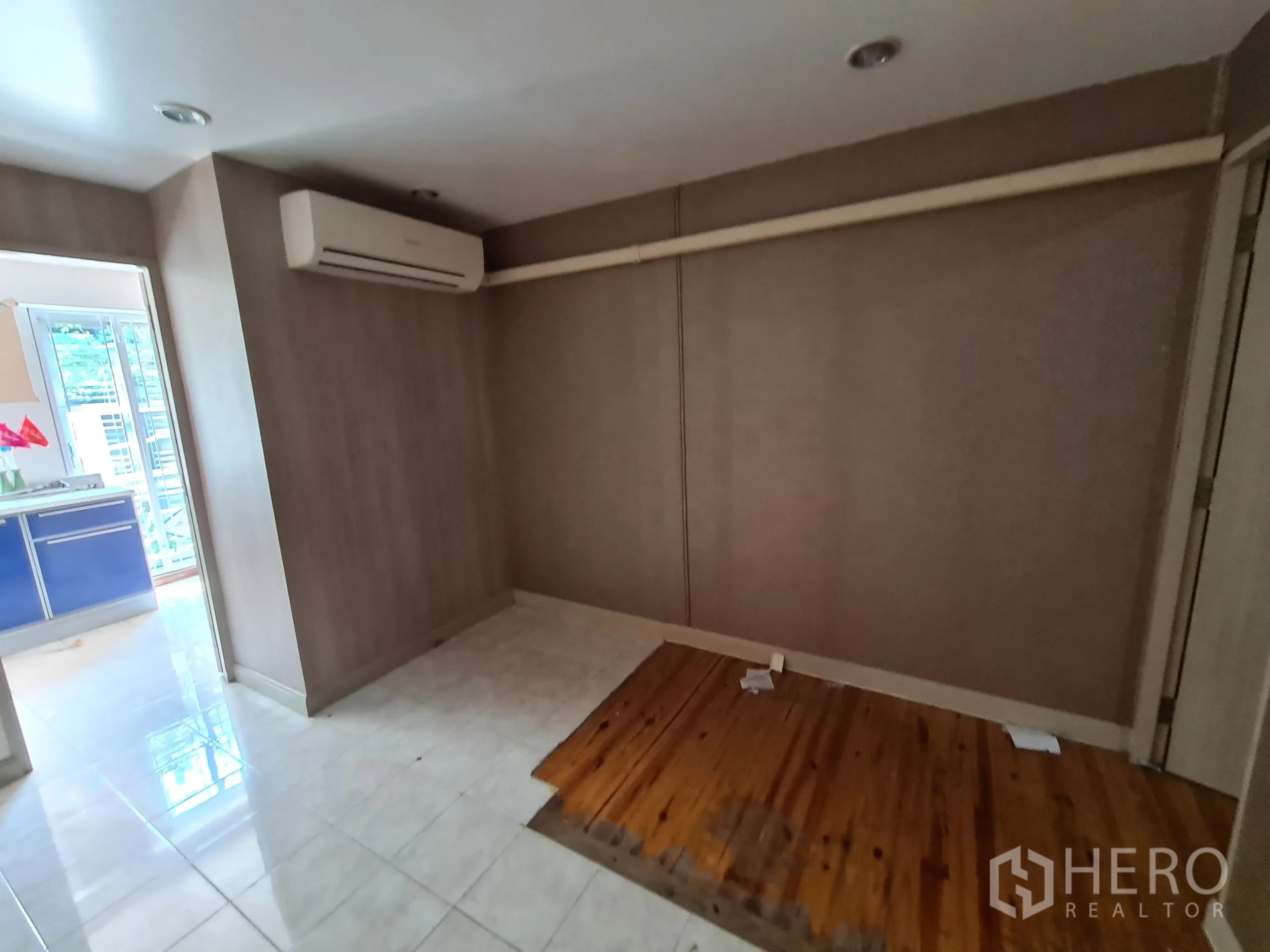 Shophouse for rent or sale in Sathon, Bangkok - Compact room with wall-mounted air-conditioner and a raised wood platform beside a bright doorway.