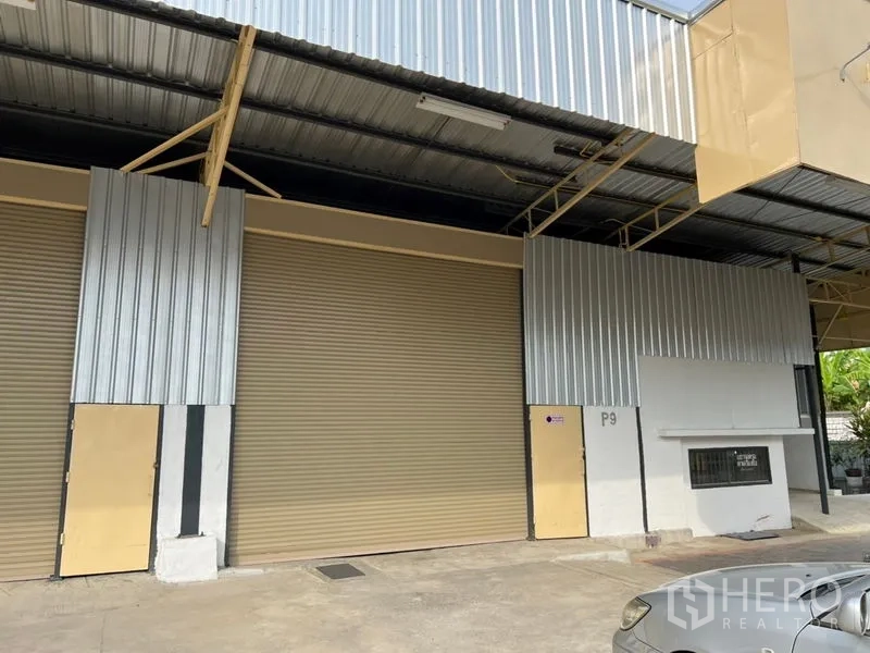 货栈 出租在Suan Luang, Bangkok - 素安鲁昂仓库外观，宽大金属卷帘门与有顶装卸区