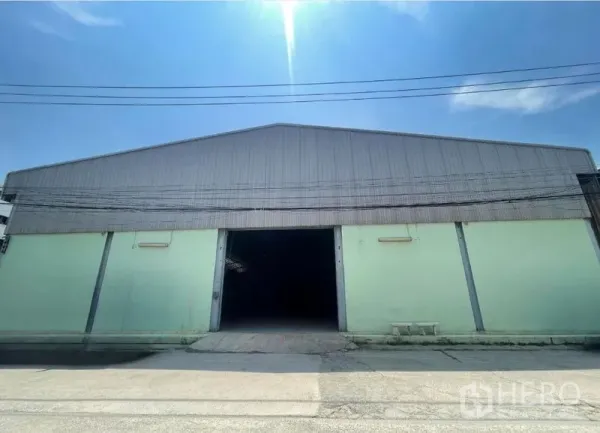 Warehouse for rent in Bang Phli, Samut Prakan - Front view of a high-roof warehouse with pale green walls and a wide loading entrance in Bang Phli.
