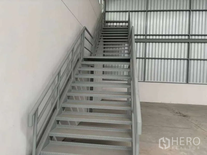 Warehouse for rent in Nikhom Phatthana, Rayong - Metal staircase providing mezzanine access inside the warehouse