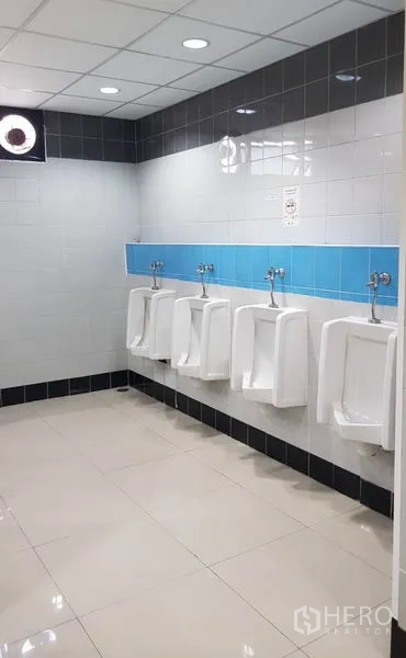 Office Space for rent in Huai Khwang, Bangkok - Row of urinals in a tiled men’s restroom with overhead lighting