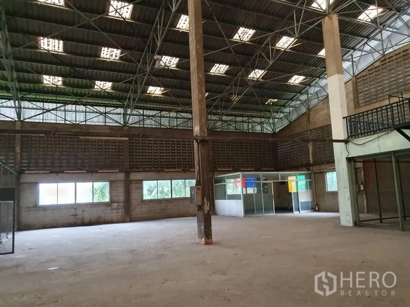 工厂 出租在Samut Prakan - 开放生产区，混凝土地面、钢柱与角落办公隔间，高挑屋顶。