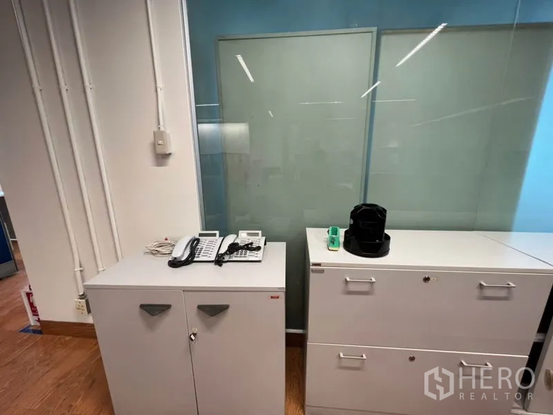Office Space for rent in Khlong Toei, Bangkok - White filing cabinets with office phones and equipment beside a glass panel.
