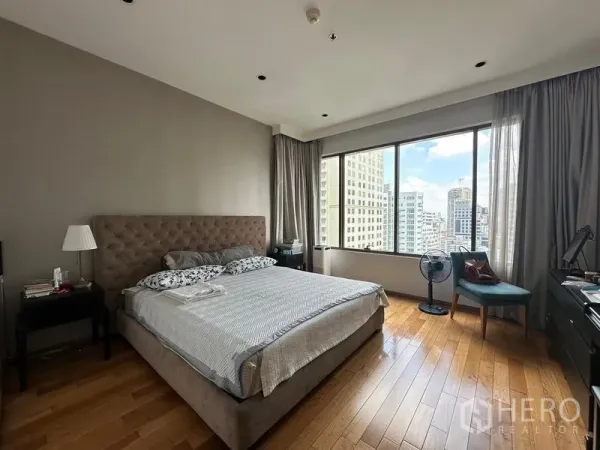 Condominium for sale in Khlong Toei, Bangkok - Spacious master bedroom with wood floors and a wide window framing city views.