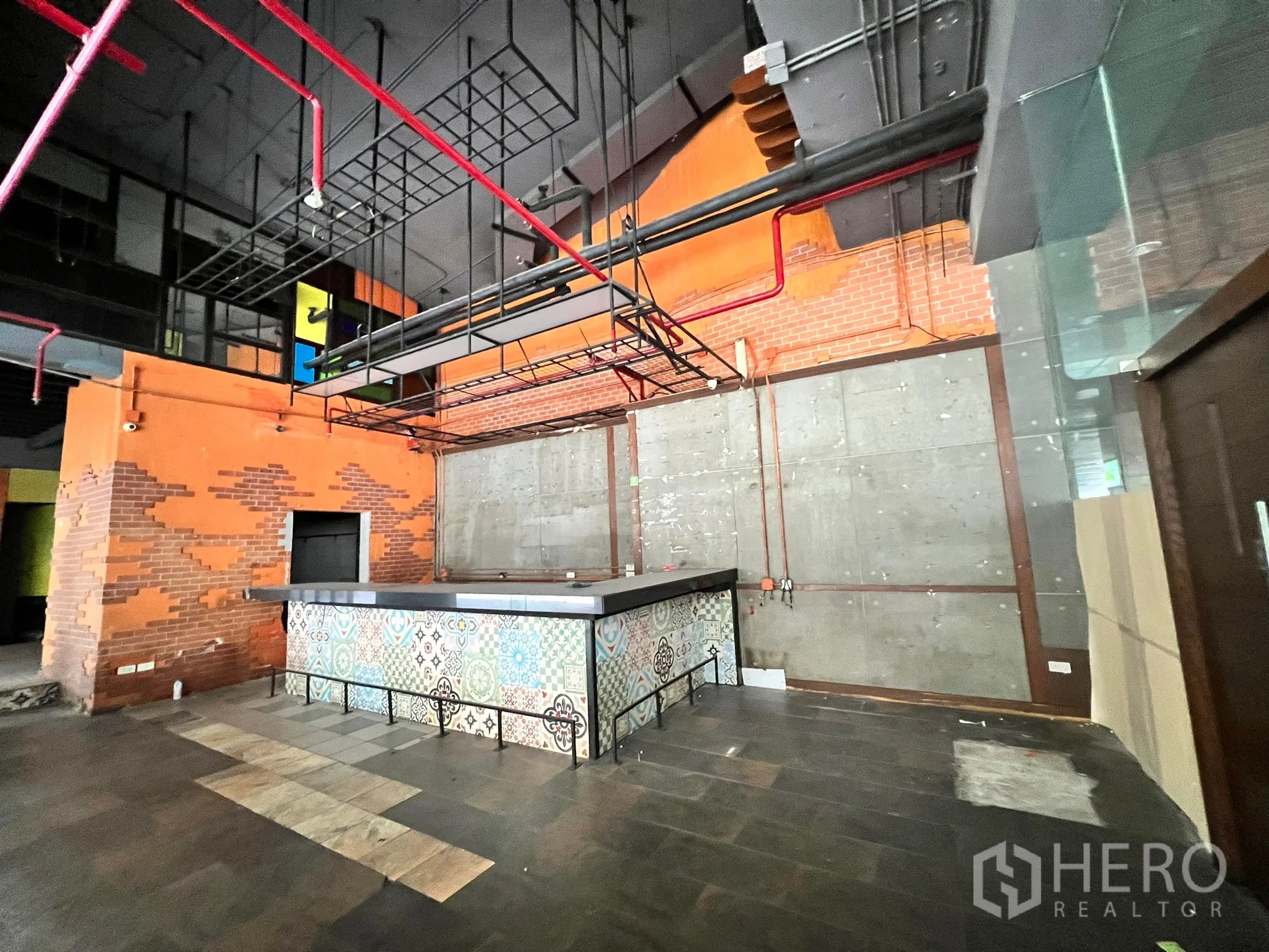 Retail Space for rent in Watthana, Bangkok - Wide view of the retail space showing a colorful tiled counter, high black ceiling and red sprinkler lines.