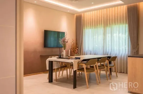 Detached House for rent or sale in Bang Kapi, Bangkok - Dining area with six-seat table, wall-mounted TV and soft cove lighting.