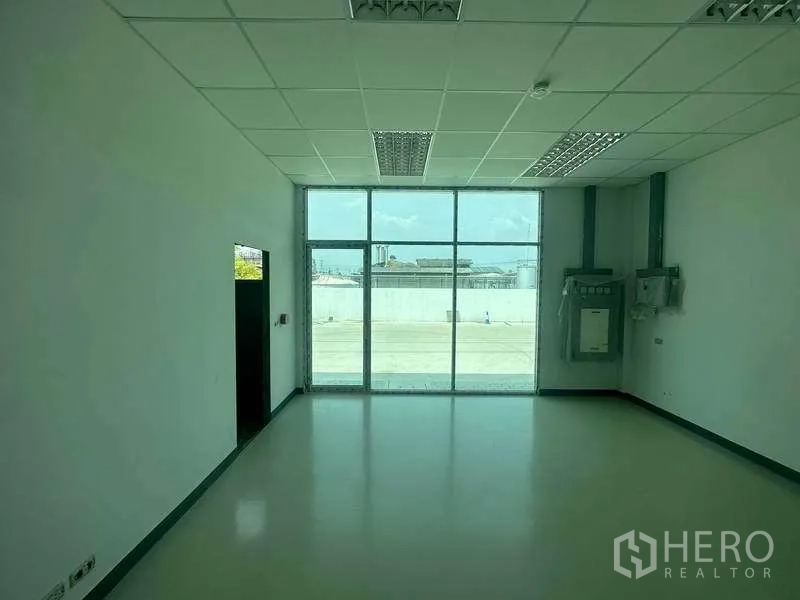 Factory for rent in Khlong Luang, Pathum Thani - Ground-floor office room with large window, suspended ceiling and electrical panels.