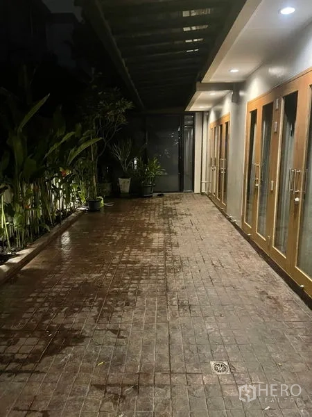 联排别墅 出租在Suan Luang, Bangkok - 带雨棚的室外走道，盆栽绿植与多扇玻璃门通向室内