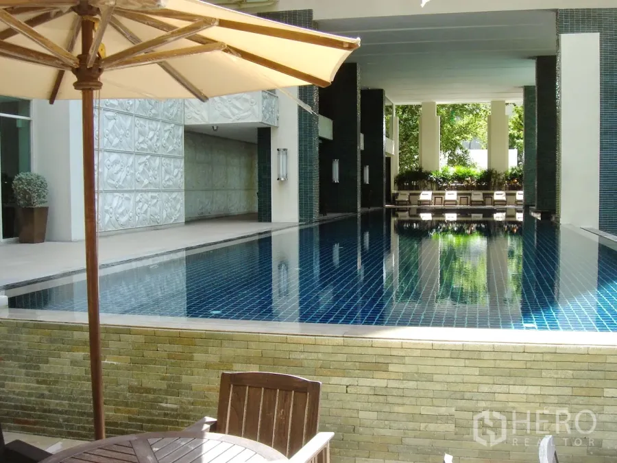 Condominium for sale in Pathum Wan, Bangkok - Covered swimming pool with sun loungers at a luxury Chidlom condominium.