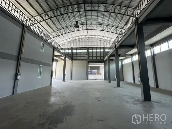 Factory for rent in Lam Luk Ka, Pathum Thani - High-clear warehouse hall with arched steel roof, concrete floor, and tall columns.