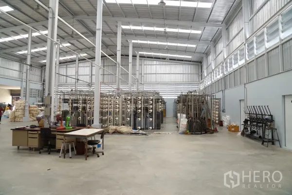 Factory for sale in Krathum Baen, Samut Sakhon - Spacious production hall with high steel roof, skylights, and industrial machines.