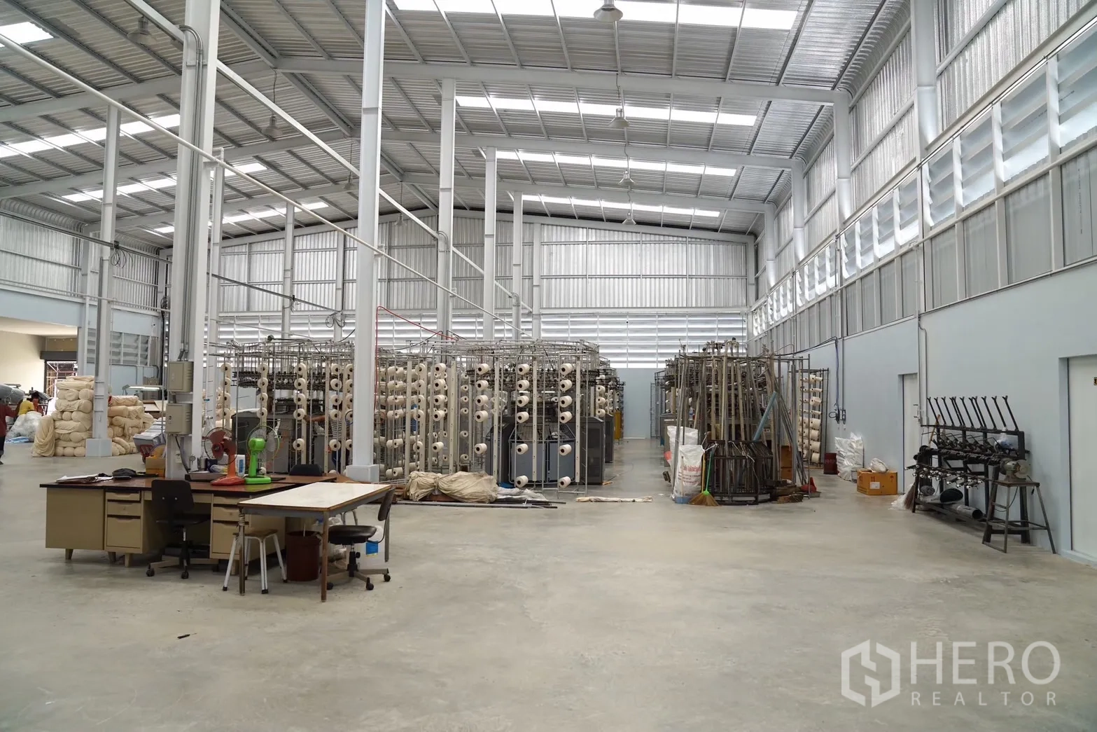 Factory for sale in Krathum Baen, Samut Sakhon - Spacious production hall with high steel roof, skylights, and industrial machines.