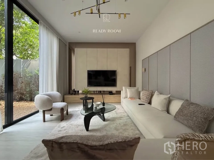 Detached House for rent in Bang Kapi, Bangkok - Lounge with long sofa, built‑in TV wall and sliding glass doors to the courtyard.