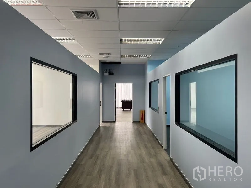 Office Space for rent - Long corridor with glass-partitioned rooms on both sides, wood-look flooring and bright fluorescent lighting.