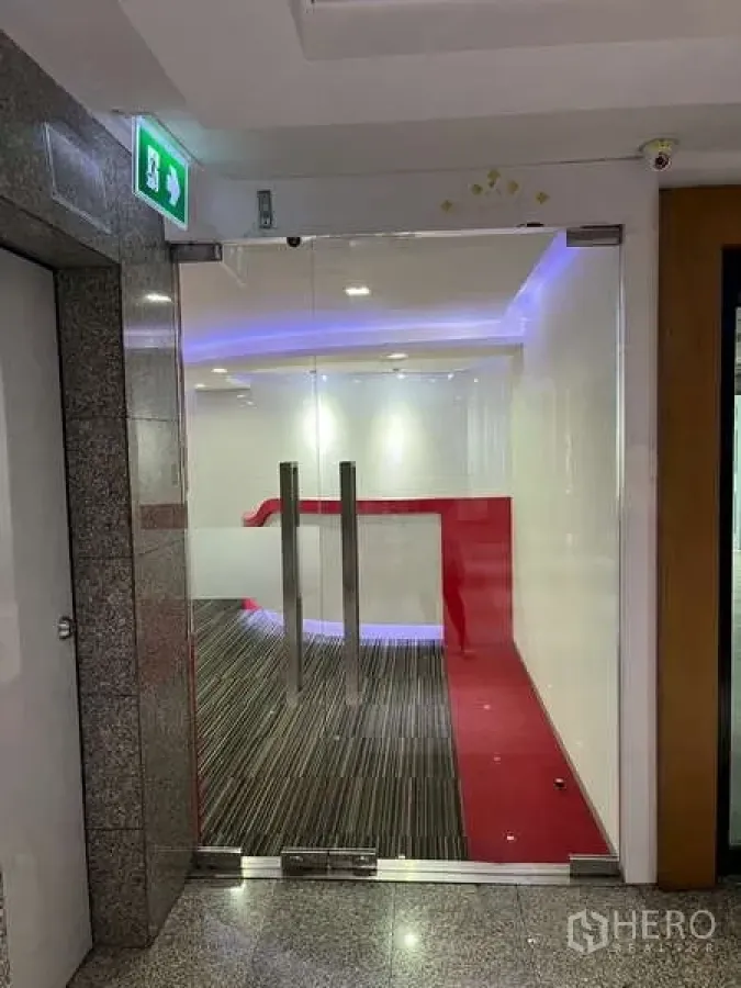Office Space for rent - Glass entry doors to the office suite with striped carpet and a red accent walkway.