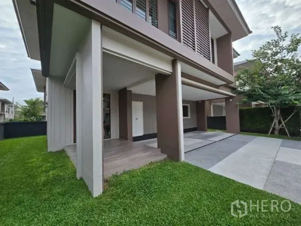 Detached House for rent in Bang Kapi, Bangkok - Side view showing green lawn, front porch and wide driveway under the upper floor.