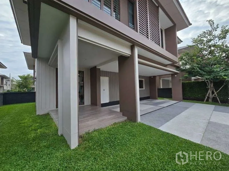 Detached House for rent in Bang Kapi, Bangkok - Side view showing green lawn, front porch and wide driveway under the upper floor.