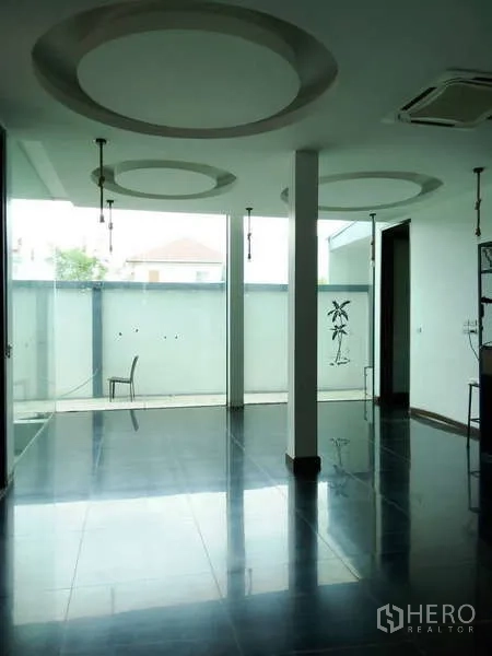 Detached House for sale in Lat Phrao, Bangkok - Minimalist room with glossy floor, columns, and frosted glass courtyard wall.