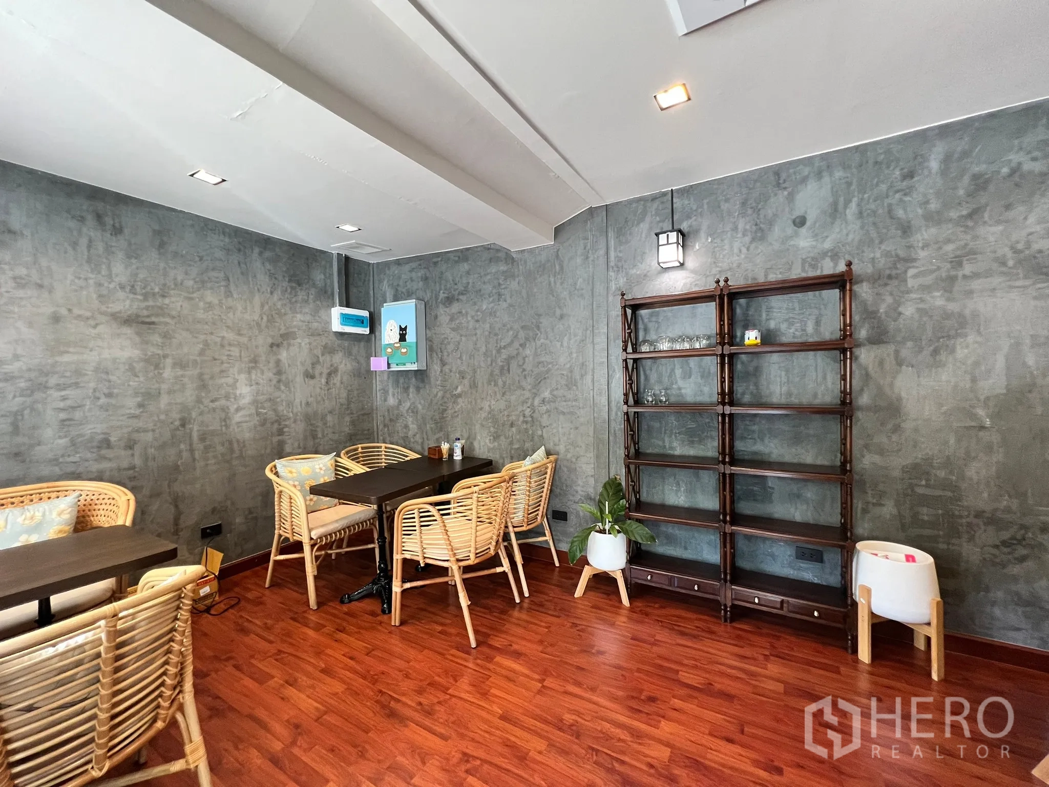 Retail Space for rent in Watthana, Bangkok - Cozy dining area with rattan chairs, polished concrete walls, wood flooring, and open shelving.