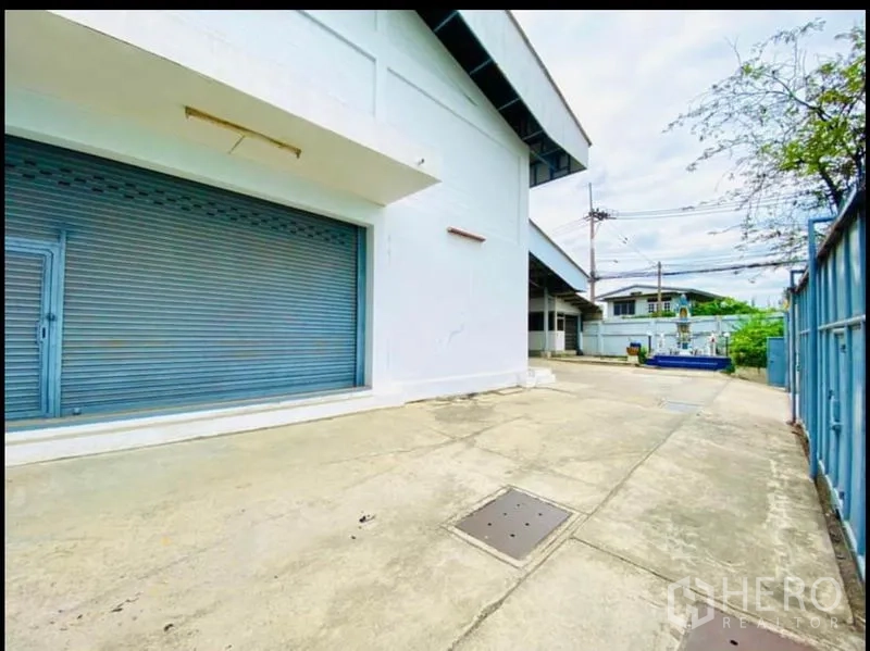 Factory for rent in Sam Phran, Nakhon Pathom - Exterior side of the factory with a roll-up loading door and service driveway.